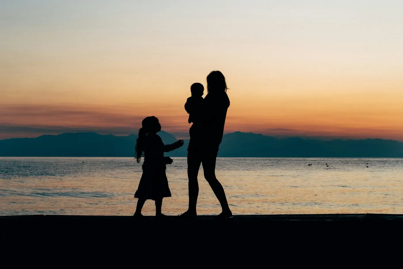 A parent and children walking along a beach shore